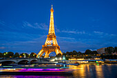 Scenic panorama of Eiffel Tower, Seine River, and pont d'lena in Paris, France; with a cruise passing by ferry