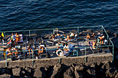 Tourists sunbathing on a recreation pier in the Bay of Naples at Sorrento, Italy.