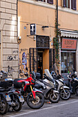 Motorcycles and motorscooters parked on a street in Rome, Italy.