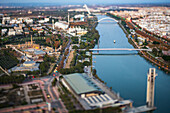 Dazzling sunset illuminates la isla de la Cartuja in Seville, highlighting the river and nearby structures with a tilt-shift lens effect.