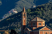 The Church of Nostra Signora della Guardia with its campanile in Levanto, Italy. Behind is a hillside village.