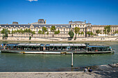 Passenger touristic cruise ship in the Seine river is moored to the pier near Louvre museum