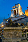 A basalt Egyptian lion statue with the Monument to Victor Emmanuel II behind in Rome, Italy.