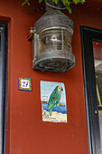 A vintage ship's light over a ceramic tile with a parrot on a residence in Marina Grande, Capri, Italy.