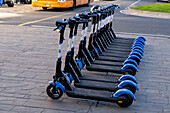 A row of rechargeable electric scooters for rent in front of the train station in La Spezia, Italy.