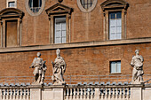 Statues on the portico around Saint Peter's Square in Vatican City in Rome, Italy with the Apostolic Palace behind.