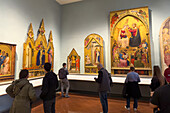 Visitors viewing Renaissance paintings in an exhibit hall in the Accademia Gallery in Florence, Italy. These paintings are in the Giovanni da Milano and Orcagna Room in the Museum.