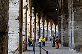 Tourists in the circular hallway by the vomitories or arched entrances/exits of the Colosseum in Rome, Italy.