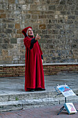 An actor in costume imitates Dante on the street in the medieval walled town of San Gimignano, Italy.