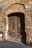 A weathered wooden door on the Via San Giovanni in the walled town of San Gimignano, Italy.