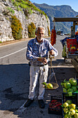 A roadside vendor weighs a giant lemon with a balance scale by the Amalfi Coast road near Positano, Italy.