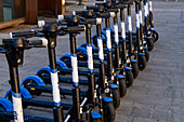 A row of rechargeable electric scooters for rent in front of the train station in La Spezia, Italy.