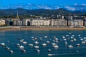 Playa de la Concha beach and fishing boats and sport fishing boats to recreational boat fishing are moored in the harbor of Donostia San Sebastian.