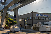 A worker powerwashes a block marble at a marble carving studion in Carrara, Italy. Another large block of marble hangs from the gantry crane.