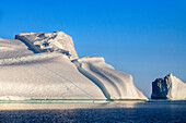 Skjoldungen Fjord. Large iceberg in scenic fjord surrounded by snow-capped mountains, Southeast coast, Greenland