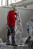 A sculptor uses a pneumatic chisel to carve a marble statue in a carving studio in Carrara, Italy.