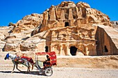 Bedouin riding horse carriage in front of the tombs of Djinn Blocks ancient tombs of Petra in Jordan