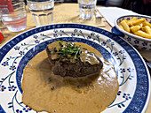 Steak with green peppercorn sauce, parsley and fried potatoes in a restarant in Florence, Italy.