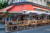 People sitting at La Liberte cafe restaurant on a street avenue in Montparnasse Paris France EU Europe