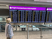 A traveler looks at the flight connections information screen at Heathrow Airport, London, England.