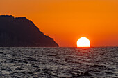 Sun setting over the ocean off the island of Capri in the Bay of Naples, Italy.