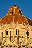 Detail of the Baptistery of St. John of the Pisa Cathedral in the Piazza dei Miracoli in Pisa, Italy. The top half of the baptistery is Gothic style, while the lower half is Romanesque.