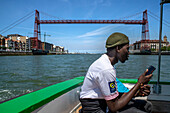 Menschen in El Gasolino, einem kleinen Boot, das Passagiere über den Fluss Nervion zwischen Portugalete und Las Arenas, Getxo, Vizcaya, Pais Vasco, Spanien, befördert.