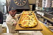 The pizzaiolo or pizza chef with a large Pizza al Taglio at the Da Franco Food Philosophy pizzeria in Sorrento, Italy.