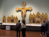 Visitors viewing Renaissance paintings in an exhibit hall in the Accademia Gallery in Florence, Italy.