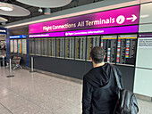 A traveler looks at the flight connections information screen at Heathrow Airport, London, England.