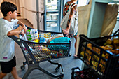 Poor and vulnerable families collecting donated products in the supermarket Rebost Solidari de Gracia, Gracia neighborhood, Barcelona, Spain, Europe. The Rebost Solidari de Gracia is a distributor entity of the Food Bank in its Sec, SERMA (fresh fruit and vegetables), cold chain (frozen and refrigerated products) and FEGA (products received from the EU) programs. An efficient management of all the food surpluses generated by the neighborhood (markets, supermarkets, shops, companies, restaurants, school canteens and others) is an important enough objective in itself, both for its use in the nei