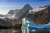 Skjoldungen Fjord. Large iceberg in scenic fjord surrounded by snow-capped mountains, Southeast coast, Greenland