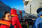 Silversea Endeavor zodiac and tourists in the coast of East Greenland in the village of Aappilattoq, South Greenland, Arctic sea.