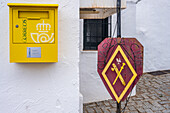 Bright yellow mailbox and historic Guardia Civil sign in Andalusian street scene