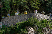 Large, colorful ceramic pots on a stone wall at a ceramic shop on the Amalfi Coast of Italy.