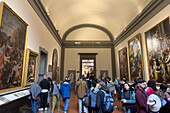 Visitors viewing Renaissance paintings in an exhibit hall in the Accademia Gallery in Florence, Italy.