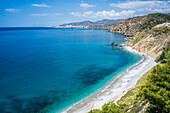 Blue waters and picturesque cliffs surrounding a serene beach setting near Nerja, Spain.