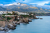 Beautiful coastal landscape featuring cliffs, tranquil sea, and mountainous backdrop in Nerja, Spain.