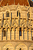 Detail of the Baptistery of St. John of the Pisa Cathedral in the Piazza dei Miracoli in Pisa, Italy. The top half of the baptistery is Gothic style, while the lower half is Romanesque.