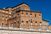 Statues on the portico around Saint Peter's Square in Vatican City in Rome, Italy with the Apostolic Palace behind.