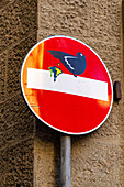 Humorous art of a bird pooping on a street sign in Florence, Italy.