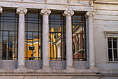 Colorful buildings are reflected in the glass of the Animosi Theater on Piazza Fabrizio de Andre in Carrara, Italy.