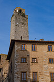 The top of the Torre Rognosa above buildings on Via San Giovanni in the medieval city of San Gemignano, Italy.