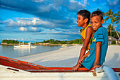 Local children and fish boats in white sand beach in of Langub Beach Malapascua island, Cebu, Philippines