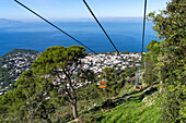 Tourists on the Monte Solaro chairlift from Anacapri to the Monte Solaro overlook on the island of Capri, Italy. The town of Anacapri is visible below.