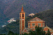 The Church of Nostra Signora della Guardia with its campanile in Levanto, Italy. Behind is a hillside village.