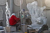 A sculptor works on a statue in a marble carving studio in Carrara, Italy.