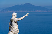 A statue of Augustus Caesar on a cliff-top patio at the Hotel Augustus Caesar in Anacapri, Capri, Italy. Mount Vesuvius is visible across the Bay of Naples.