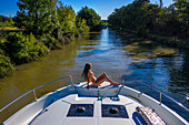 Aerial view girl sunbathing on the deck of a boat. Canal du Midi near Carcassonne Aude South of France southern waterway waterways holidaymakers queue for a boat trip on the river, France, Europe