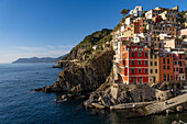 Colorful buildings overlooking the harbor and Lingurian Sea in Riomaggiore, Cinque Terre, Italy.